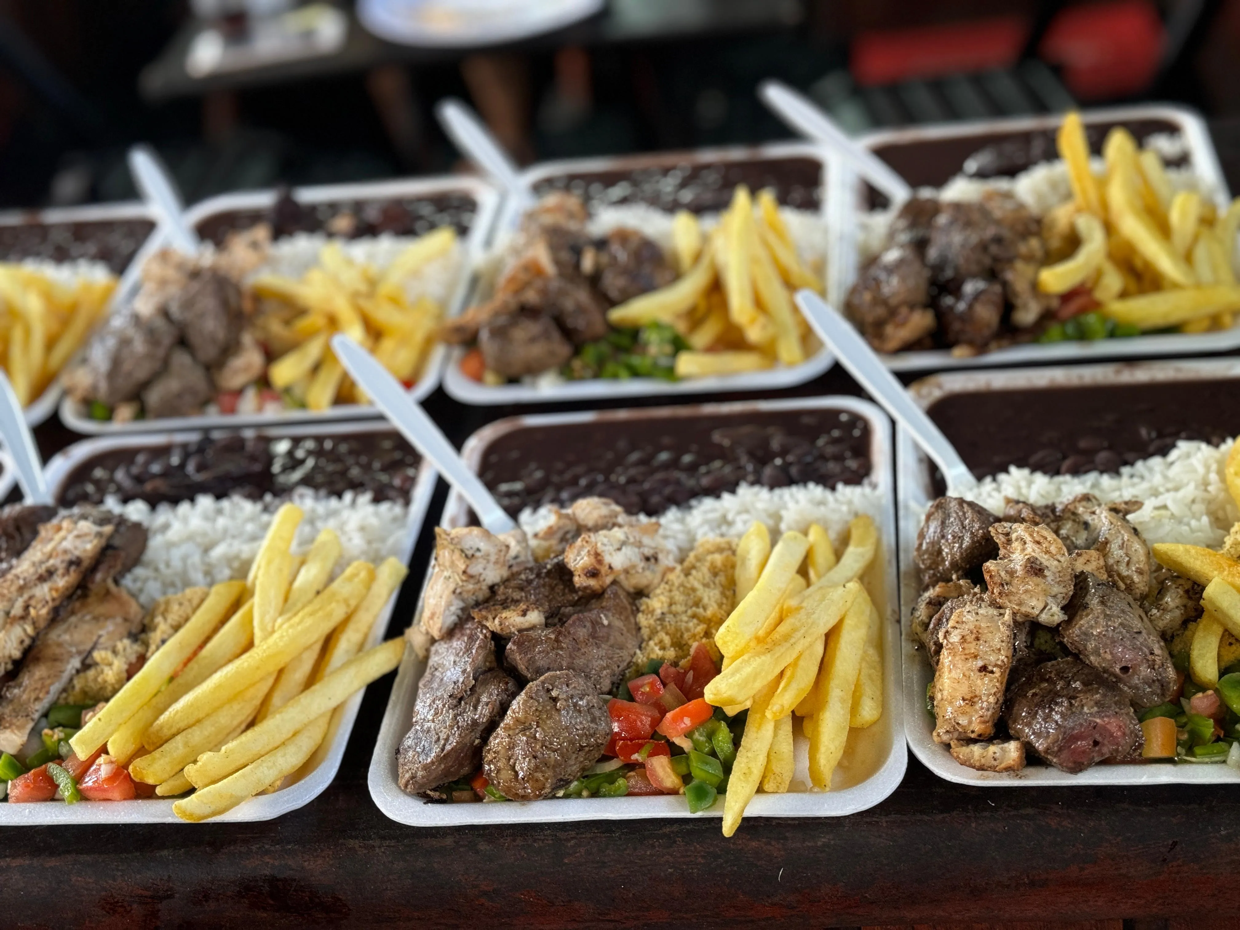 Marmitas servidas a bordo com arroz, feijão, carne grelhada, batata frita e salada