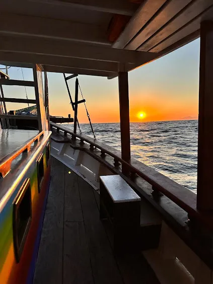 Deck de madeira do barco com o sol se pondo no mar